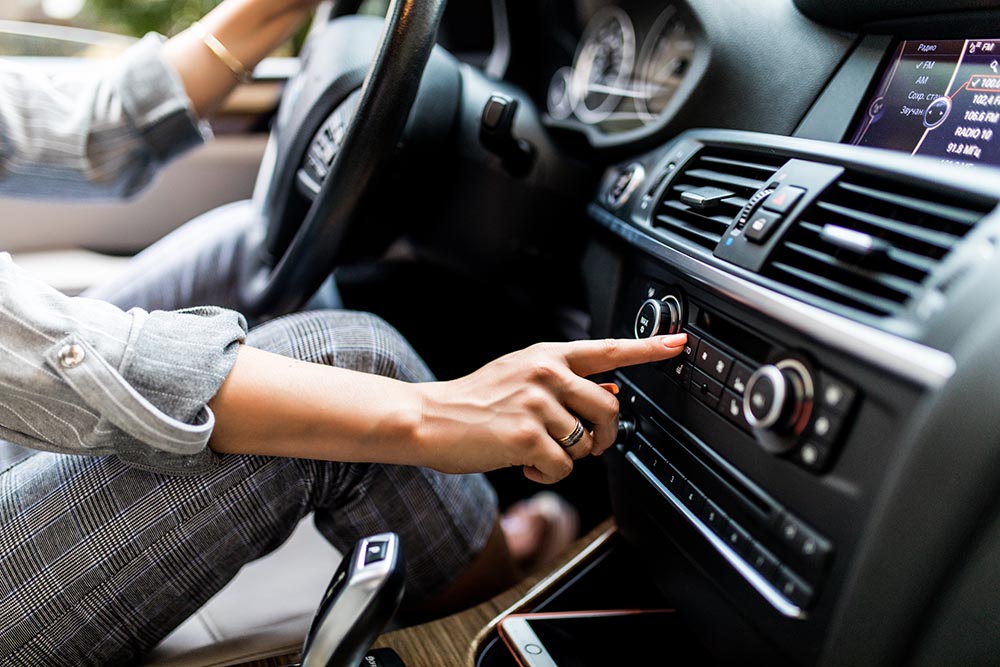 car dashboard radio closeup woman sets up radio while driving car 拷貝 https://gonews.com.tw/wp-content/uploads/2021/05/開車防疫_01-拷貝-optimized.jpg